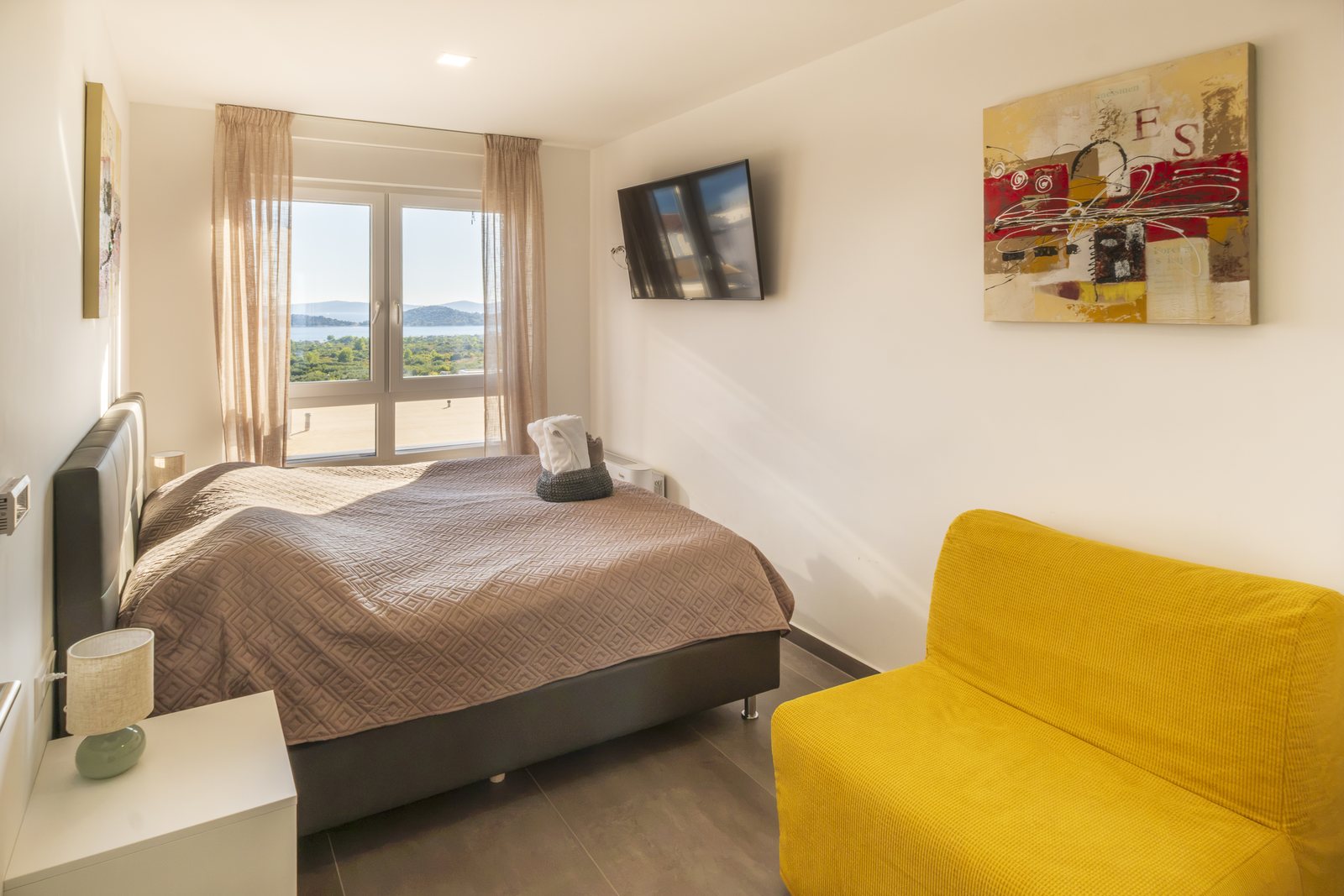Bedroom 2, with a yellow sofa and the sea through the window