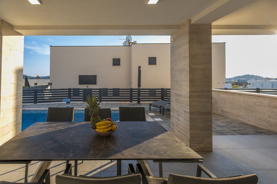The covered outdoor dining table beside the pool