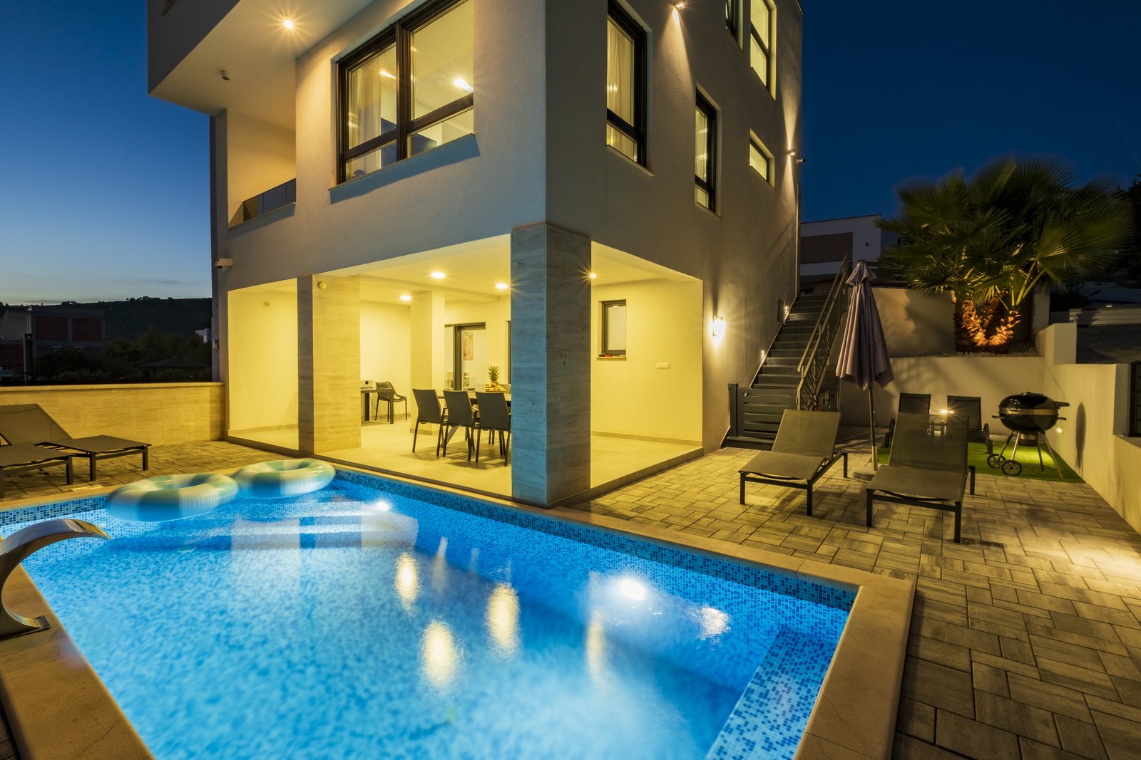 The pool and the villa in the blue hour, with the lights on