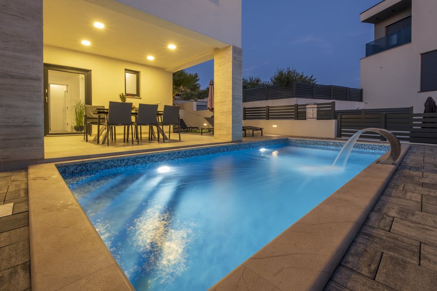 The pool lit up in the evening, with the dining area behind it