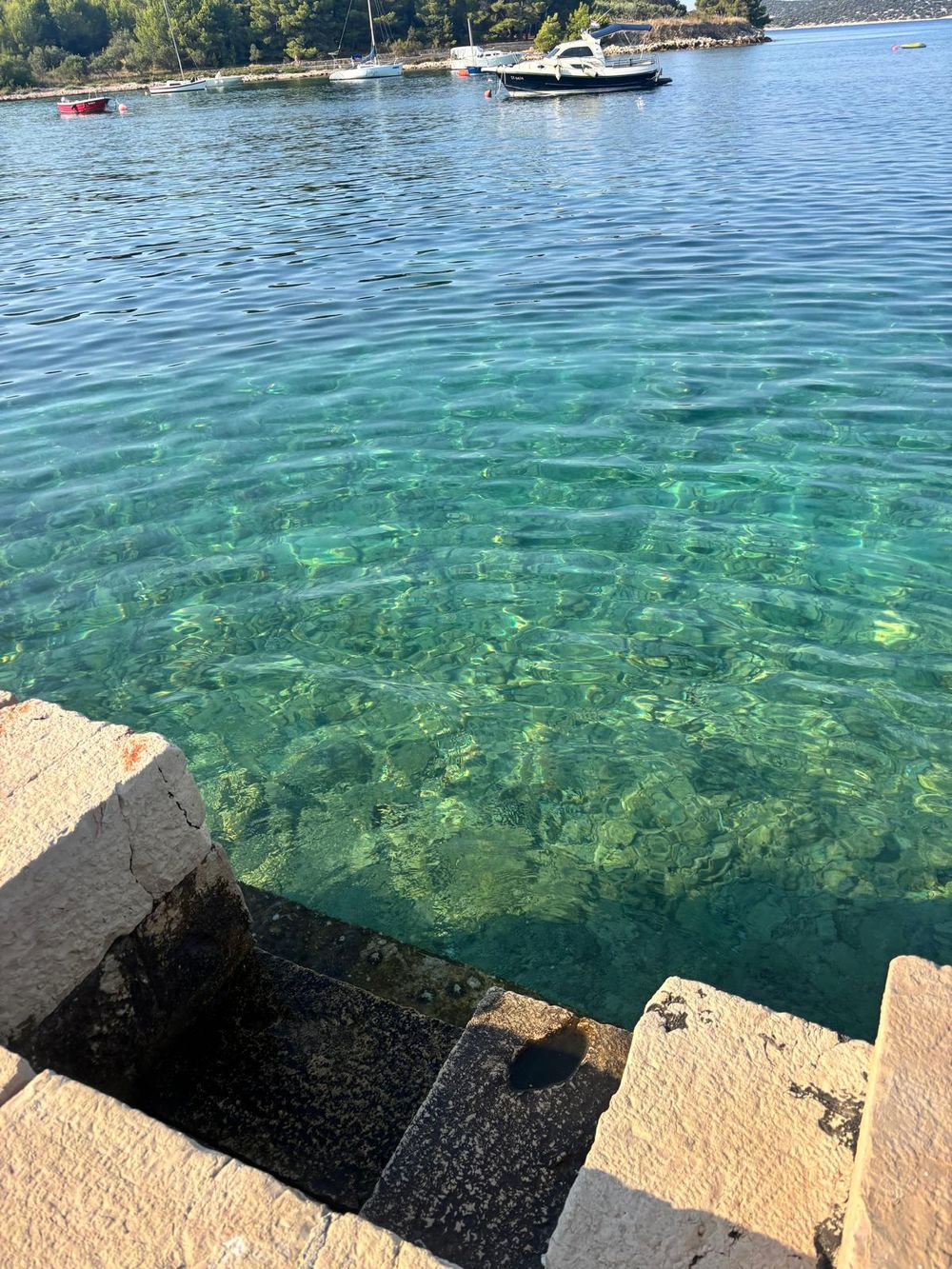 Klares türkisfarbenes Wasser an einem Steinsteg